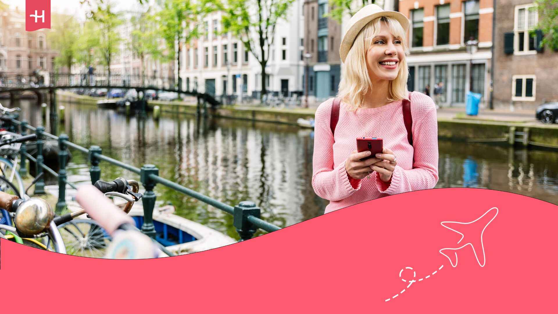 Voyageuse souriante sur le quai à Amsterdam utilisant son téléphone avec l'itinérance des données