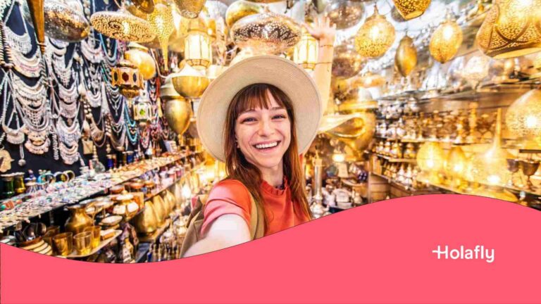 Une touriste avec un chapeau prenant un selfie dans un souk au Maroc