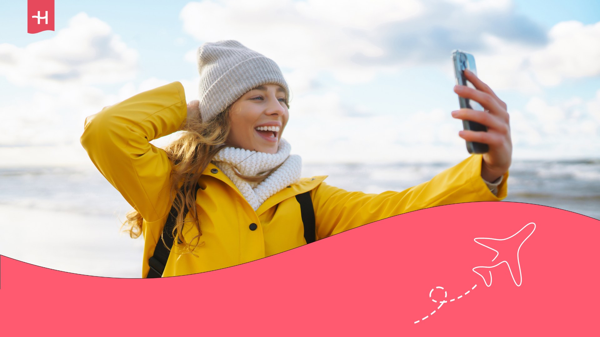 Une femme portant un bonnet se prenant en photo avec son téléphone portable en vacances