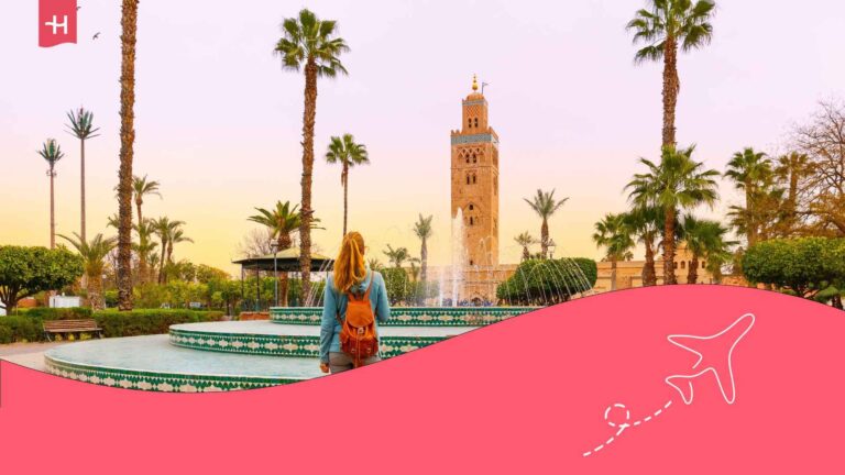 Une femme se tenant face à une fontaine à Marrakech avec la Mosquée Koutoubia en arrière plan