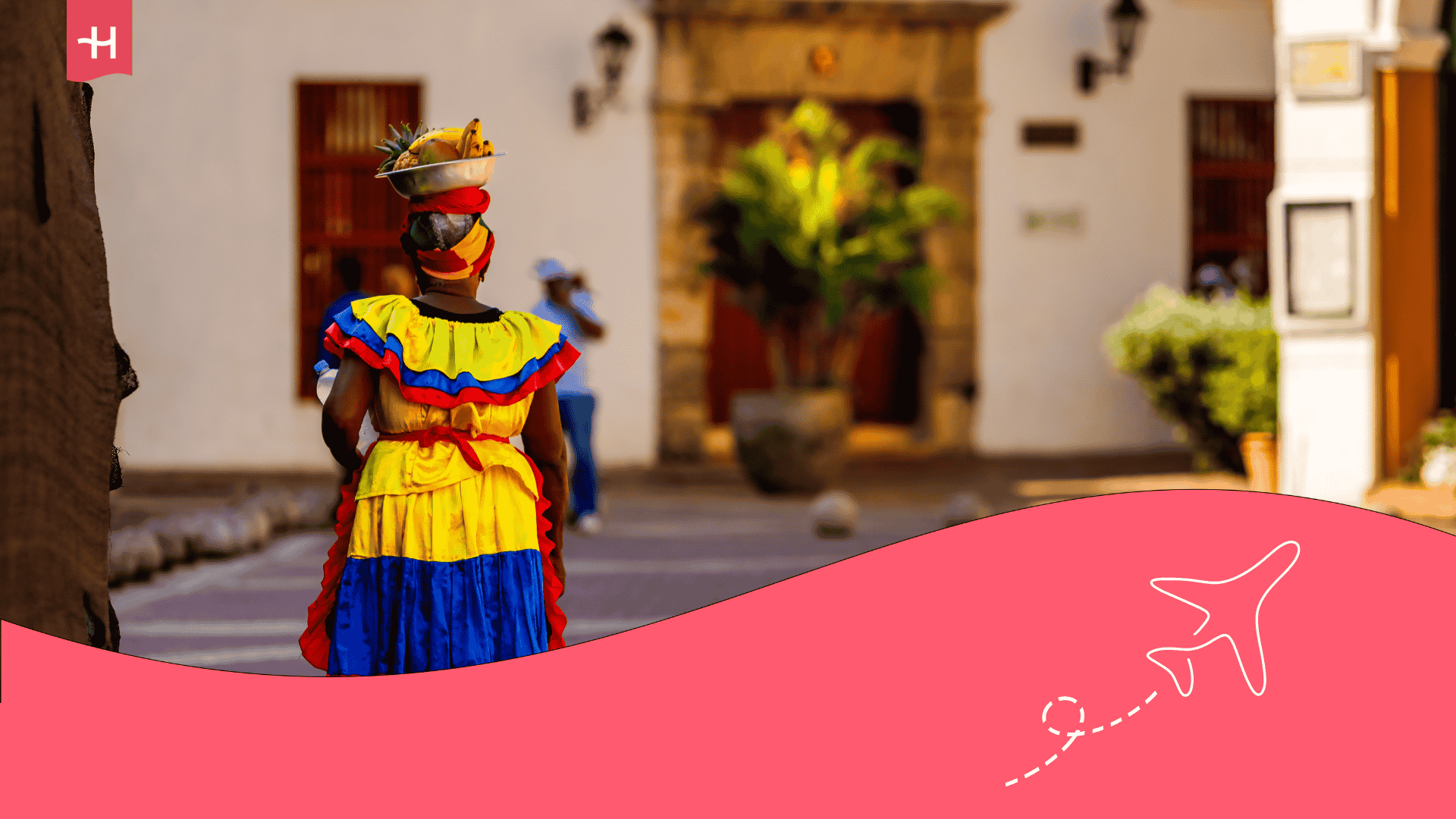 Femme marchant de dos portant une robe aux couleurs du drapeau colombien avec un panier de fruit sur la tête