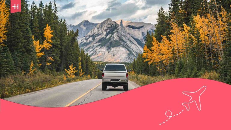 Vue arrière d'un pick-up conduisant sur route dans la forêt automnale et les montagnes rocheuses par beau temps au parc national Banff en Alberta au Canada