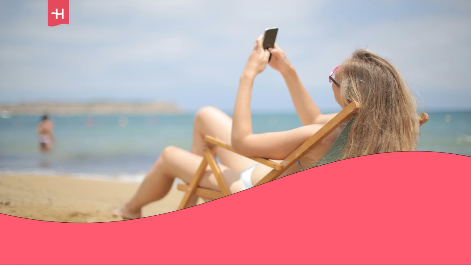 Jeune voyageuse assise sur un transat sur une plage et consultant son portable