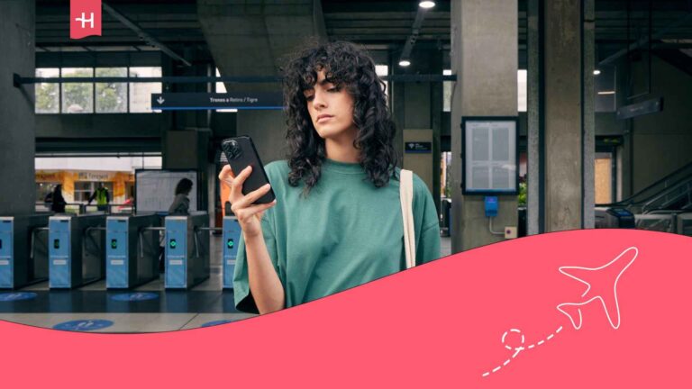 Jeune voyageuse dans une gare regardant son smartphone