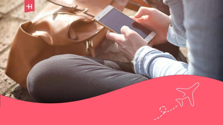 Femme assise en tailleur et tenant son smartphone dans les mains