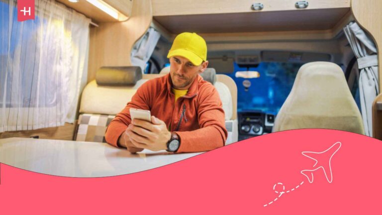 Un homme assis dans un camping car et regardant l'écran de son smartphone
