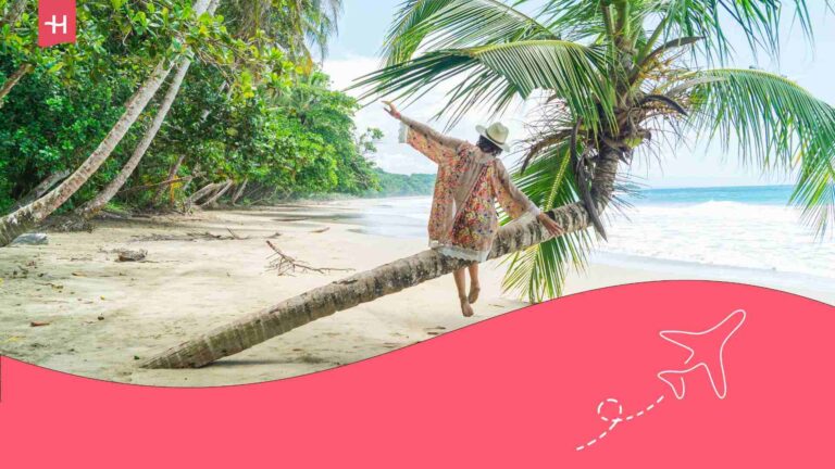 Voyageuse sur une plage au Costa Rica assise sur le tronc d'un palmier