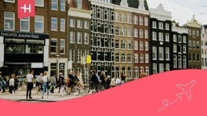 Des bâtiments colorés et des gens qui se promènent à pied ou à vélo dans la ville d'Amsterdam.