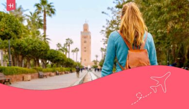 Voyageuse de dos avec sac à dos admirant le minaret de la mosquée Koutoubia à Marrakech