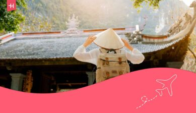 Voyageuse de dos regardant un temple et portant un chapeau conique vietnamien