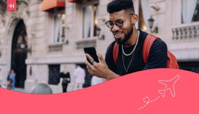 Homme avec lunettes souriant devant son smartphone dans une rue urbaine