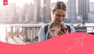 Jeune femme souriante la tente penchée sur son GSM utilisant une eSIM Proximus