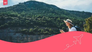 Une jeune femme en voyage assise dans la nature et regardant son téléphone en roaming avec Proximus