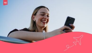 Jeune femme souriante regardant l'écran de son GSM en voyage avec le roaming Scarlet