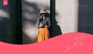 Femme souriante adossée à un mur utilisant son GSM avec une eSIM Vodafone