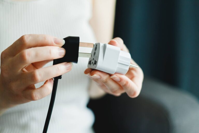 Main d'une femme branchant une prise à un adaptateur