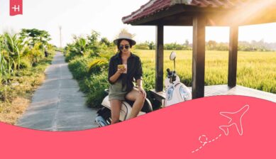 Jeune femme en voyage assise sur un scooter et regardant le GPS sur son GSM connecté avec le roaming Digi