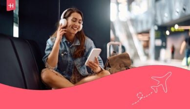 Femme souriante avec ses écouteurs regardant l'écran de son smartphone dans un aéorport