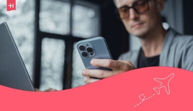 Homme devant son ordinateur portable regardant l'écran de son iPhone