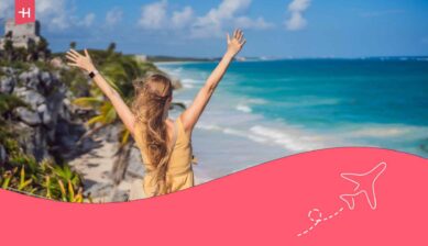 Femme de dos, levant les bras et profitant de la vue ville fortifiée maya précolombienne de Tulum, Quintana Roo, Mexique,