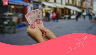 Une main d'homme tenant des billets de 50 pesos mexicain avec rue animée en arrière plan