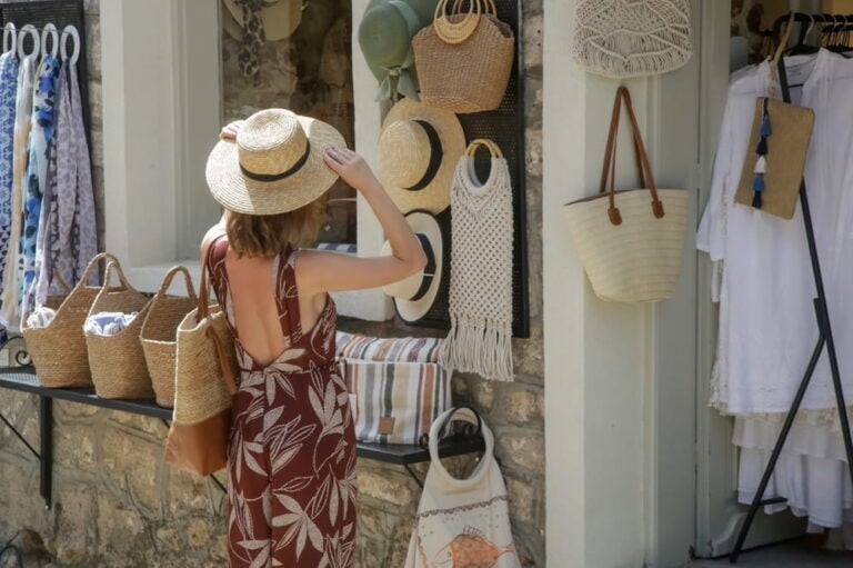 Jeune femme choisissant un chapeau d'été en paille à la boutique de souvenirs en Grèce