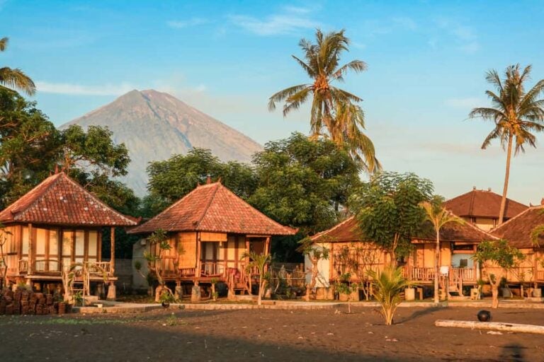 Bungalows traditionnels en bois sur une plage de sable noir face au volcan Agung à Amed.