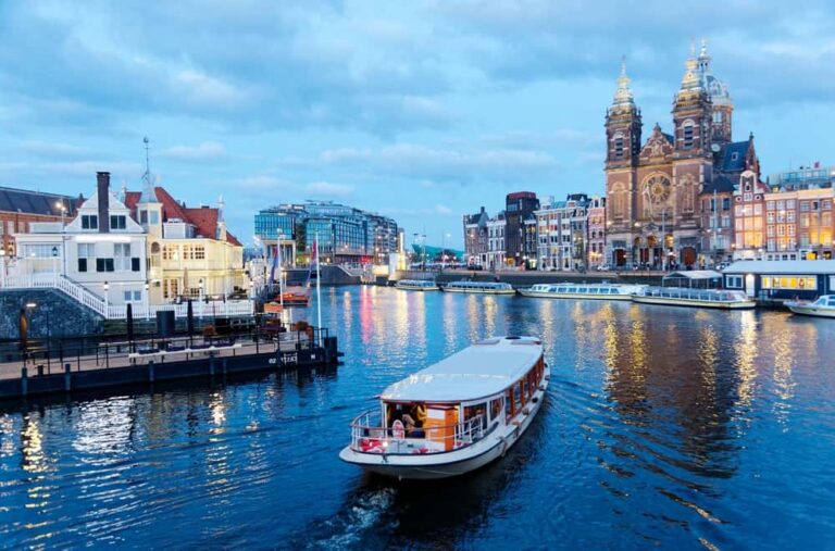 Coucher de soleil au port de la gare centrale d'Amsterdam, avec des bateaux de canal glissant sur l'eau