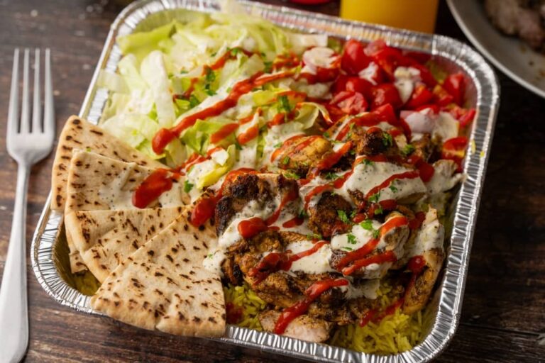 Barquette de poulet, riz et pita nappée de sauce blanche, typique des stands halal new-yorkais.
