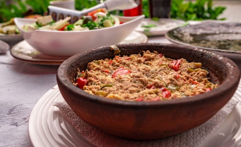 Plat traditionnel de fërgesë dans un bol en terre cuite, typique de la cuisine albanaise.