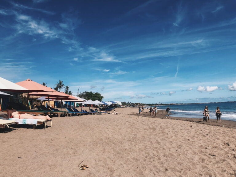 Transats et parasols installés sur le sable d'une plage animée de la côte ouest.