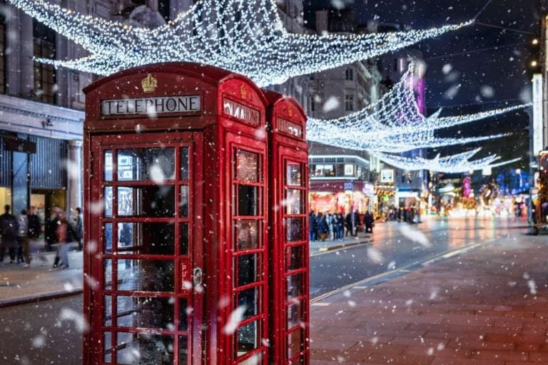 Cabine téléphonique rouge sous la neige et les illuminations de Noël dans une rue londonienne