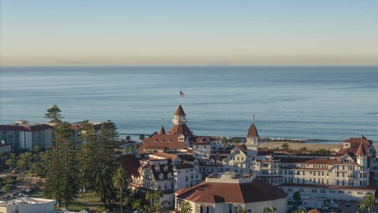 Vue aérienne de l’Hotel del Coronado, vaste complexe hôtelier de style victorien aux tourelles rouges, au bord de la plage à San Diego.