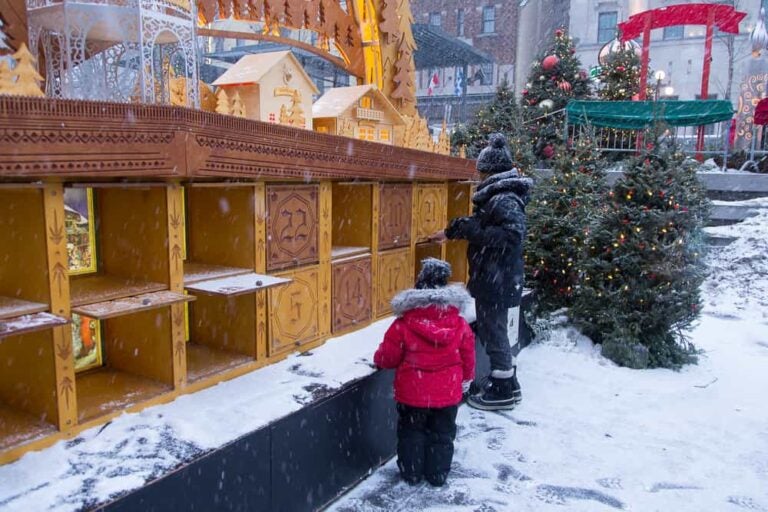 Enfants dans la neige devant un calendrier de l'Avent géant en bois au marché de Noël de Québec
