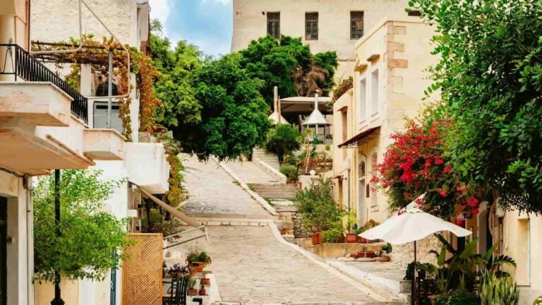 Ruelle étroite pavée de pierre dans la vieille ville de Réthymnon, en Crète, bordée de pots de fleurs et de bâtiments traditionnels