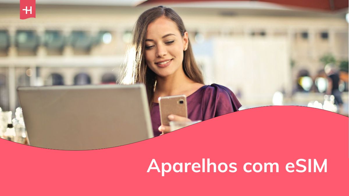 Uma jovem sorridente na frente de um laptop, olhando para o telefone