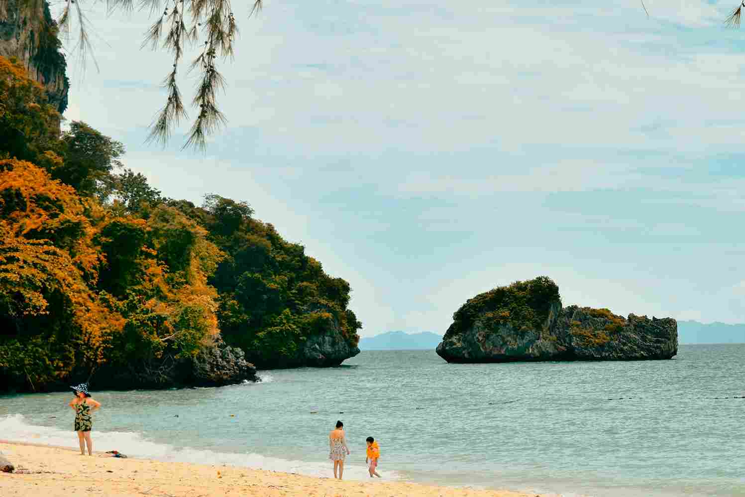 Uma praia na Tailândia com turistas curtindo-a.