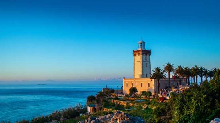 Farol do Cabo Spartel ao pôr-do-sol, com palmeiras e vista para o mar, em Tanger