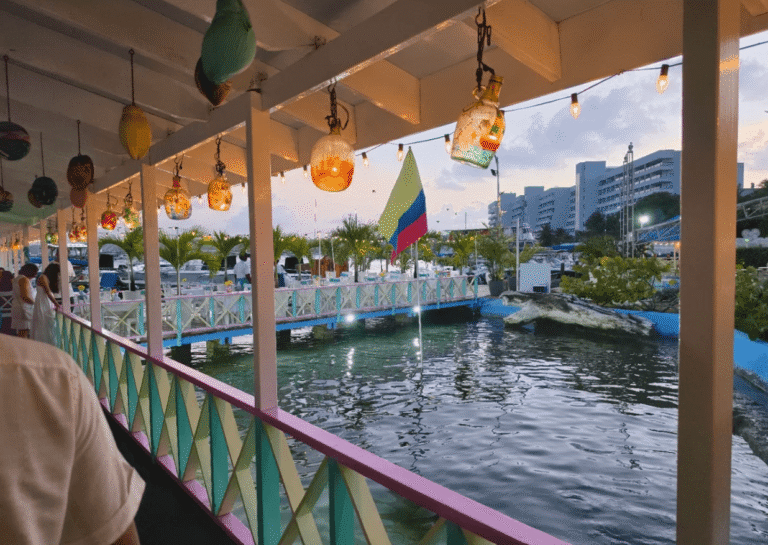Esta é a entrada do restaurante La Regatta. Próximo à bandeira, encontram-se algumas mesas reservadas para casais. As mesas para famílias ficam no interior do restaurante.
