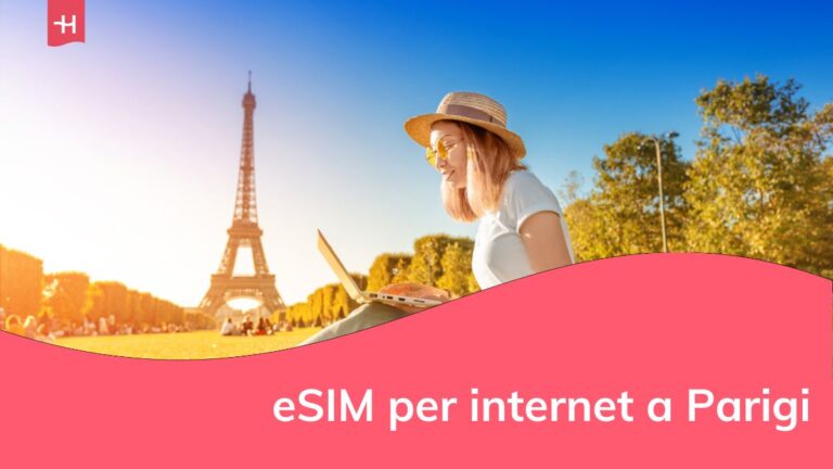 Una ragazza asiatica lavora al computer portatile seduta sull'erba del Champ de Mars a Parigi, con vista sulla Torre Eiffel al tramonto.
