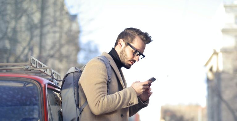 Uomo che consulta il suo cellulare all'aperto