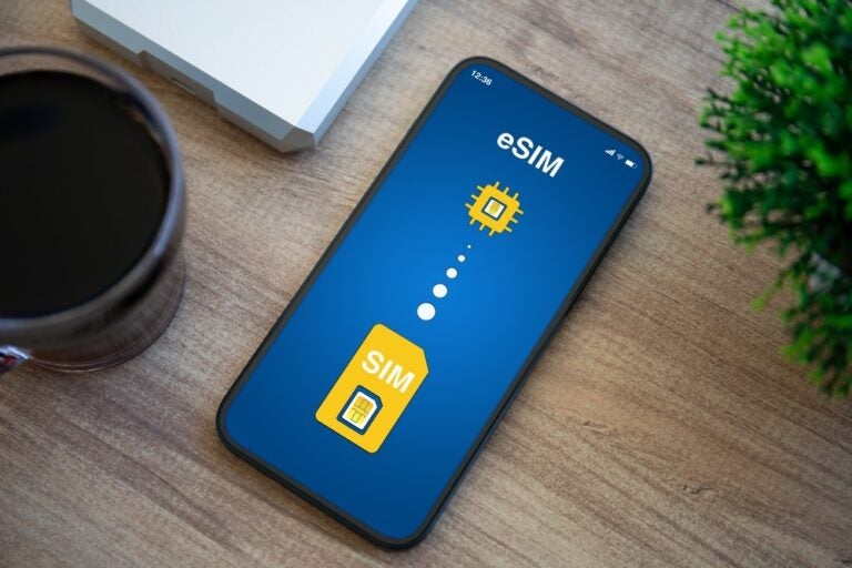 Telefono con la scheda SIM sul display eSIM, sullo sfondo un tavolo di legno di un ufficio.
