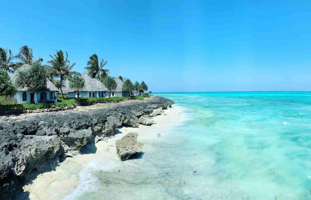 Spiaggia rocciosa con capanne affacciate sul mare blu di Zanzibar