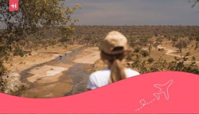 Turista bionda che osserva gli elefanti lungo il fiume Tarangire in Tanzania, Africa, durante un safari