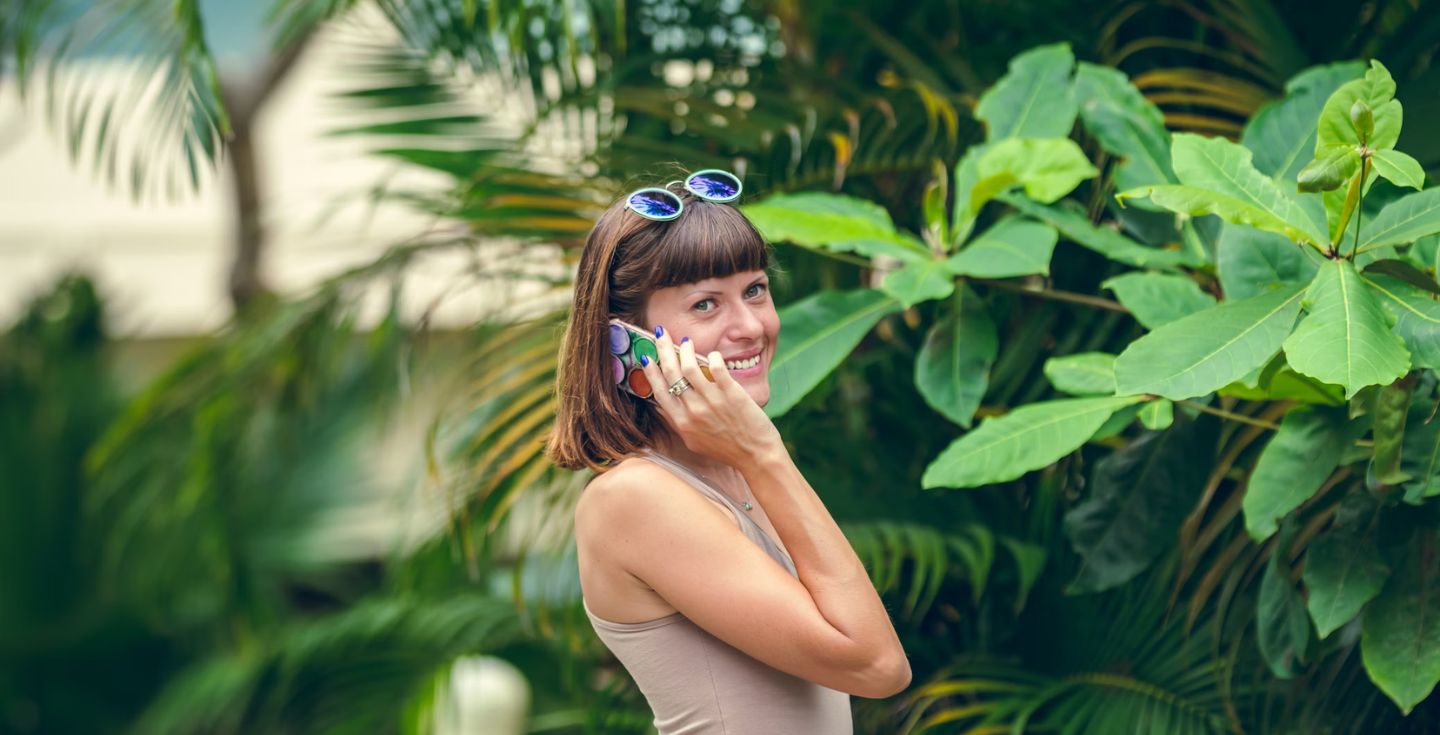 Donna che parla al cellulare davanti agli alberi