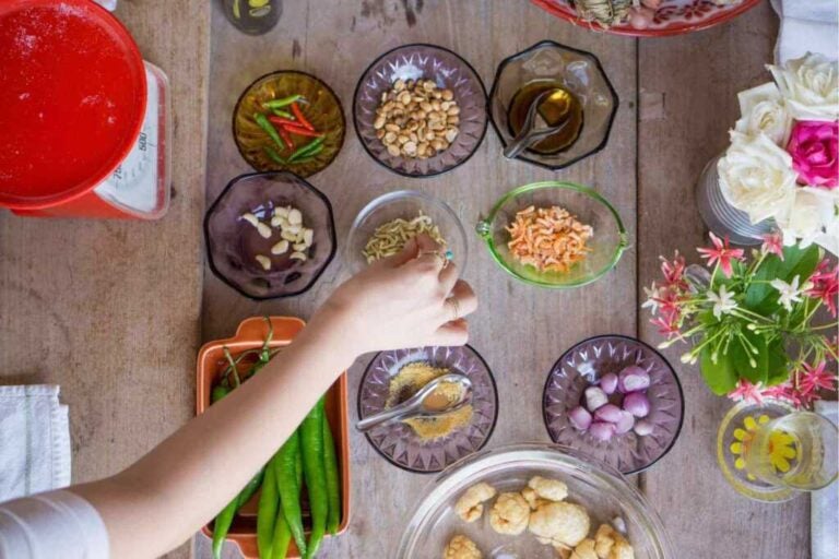 Persona che dispone gli ingredienti tipici thailandesi su un tavolo.