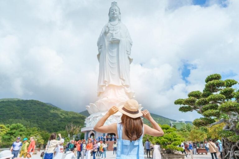 Donna in visita al tempio della Pagoda Linh Ung o Lady big Buddha. Turista con abito blu e cappello in viaggio nella città di Da Nang. Concetto di viaggio sul Vietnam e il Sud-Est asiatico