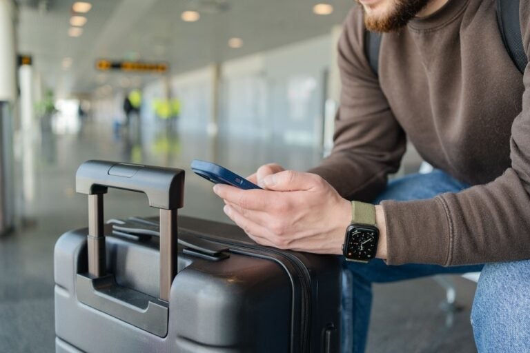 Un uomo che si rilassa all'aeroporto con una borsa e un cellulare.