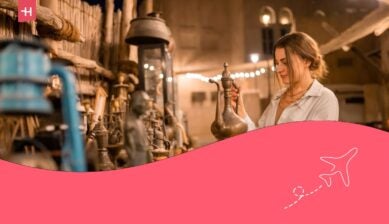 Turista donna che passeggia nel mercato arabo vicino ad Al Seef con stoviglie, lampade e lanterne in stile antico