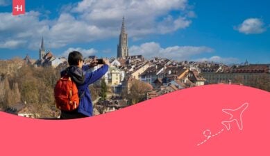 Vista posteriore di un giovane turista con zaino che scatta una foto con lo smartphone nella città vecchia di Berna, capitale della Svizzera.